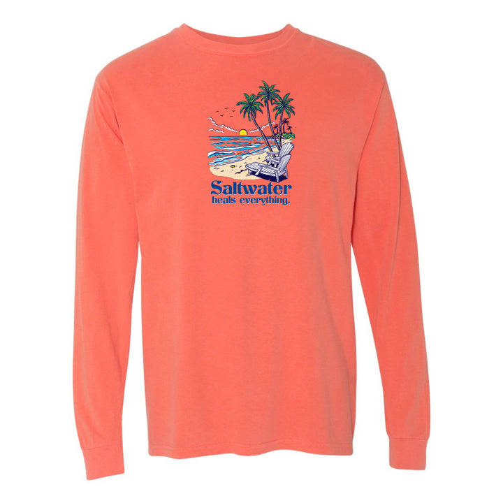 Coral long-sleeve shirt with a beach graphic and 'Saltwater heals everything' text on a white background