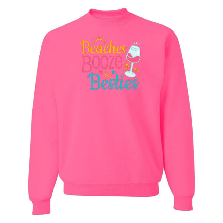 Pink sweatshirt with 'Beaches Booze & Besties' text and wine glass graphic on a white background