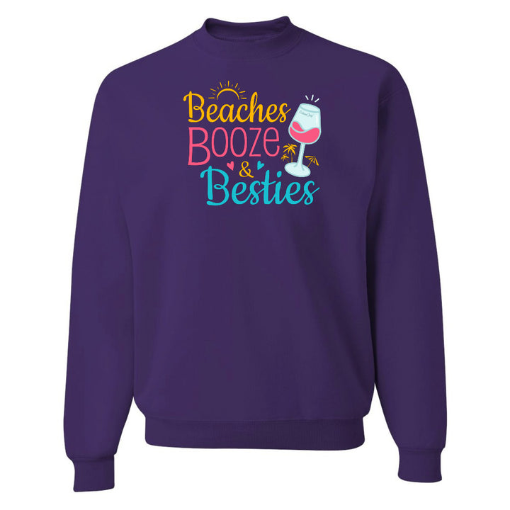 Purple sweatshirt with 'Beaches Booze & Besties' text and wine glass graphic on a white background