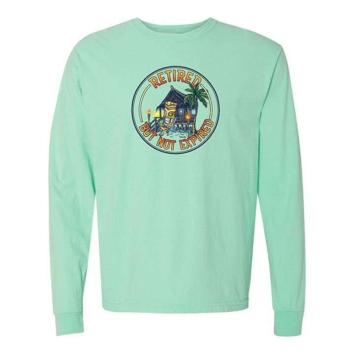 Mint green long-sleeve shirt with a tropical graphic and 'Retired but not expired' text on a white background.