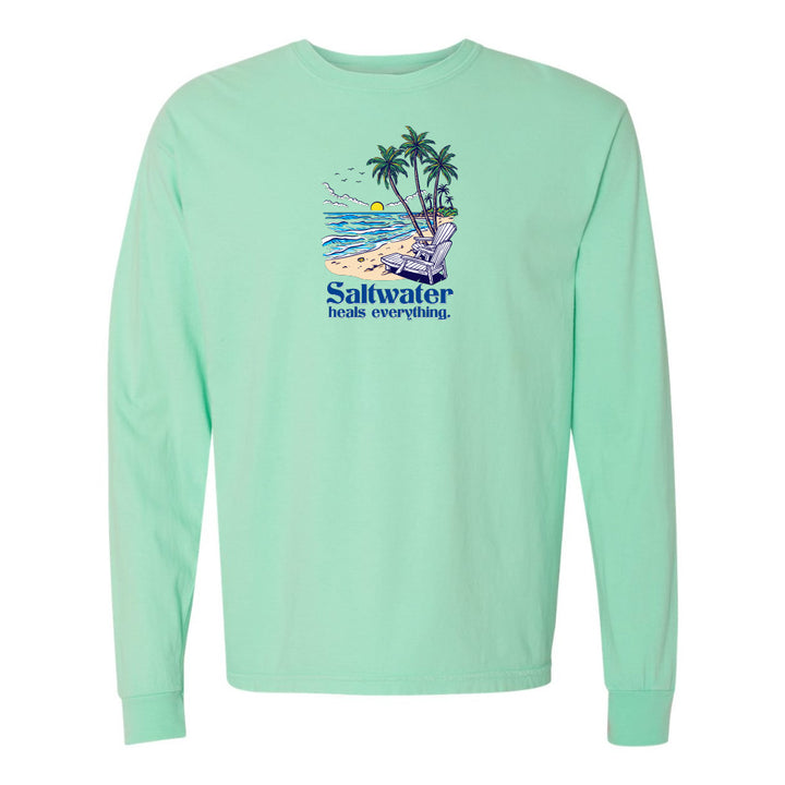 Mint green long-sleeve shirt with a beach graphic and 'Saltwater heals everything' text on a white background.