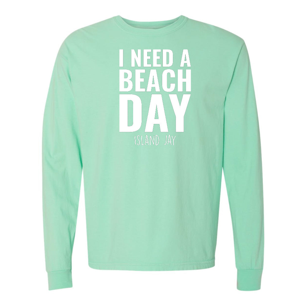Mint green long-sleeve shirt with 'I NEED A BEACH DAY' text on a white background