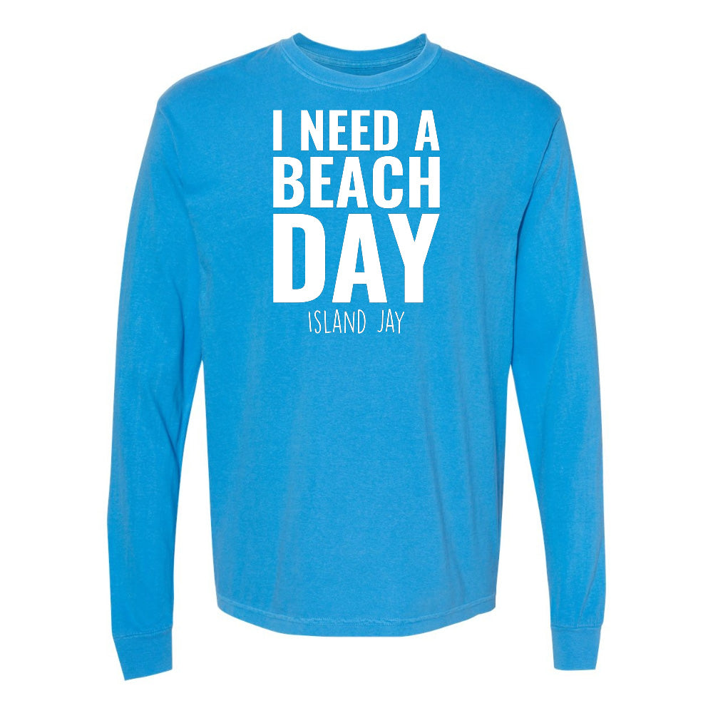 Blue long-sleeve shirt with 'I NEED A BEACH DAY' text on a white background
