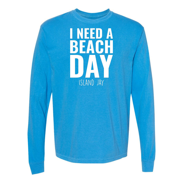 Blue long-sleeve shirt with 'I NEED A BEACH DAY' text on a white background