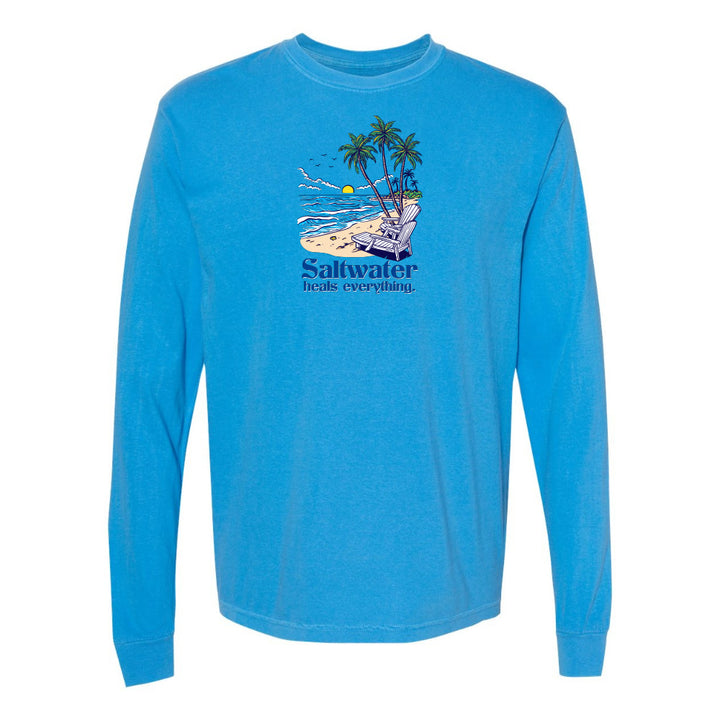Blue long-sleeve shirt with a beach graphic and 'Saltwater heals everything' text on a white background