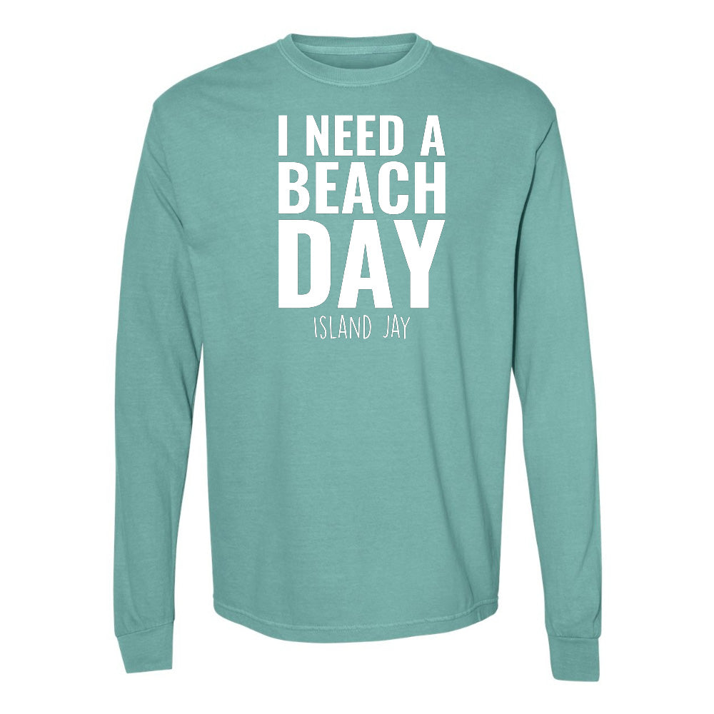 Teal long-sleeve shirt with 'I NEED A BEACH DAY' text on a white background