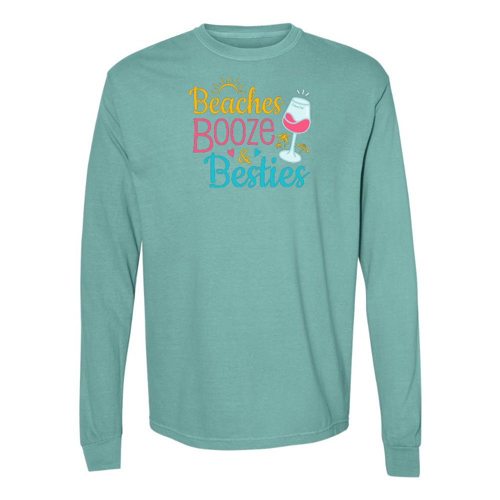 Teal long-sleeve shirt with 'Beaches Booze & Besties' text and wine glass graphic on a white background
