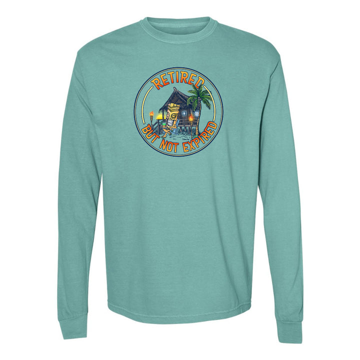 Teal long-sleeve shirt with a tropical graphic and 'Retired But Not Expired' text on a white background