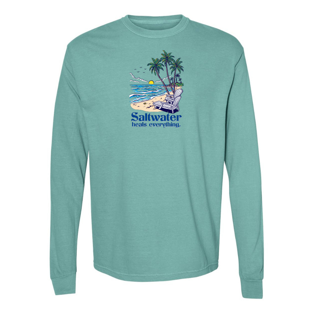 Teal long-sleeve shirt with a beach graphic and 'Saltwater heals everything' text on a white background