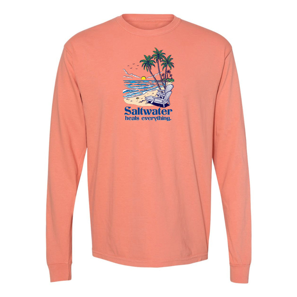 Coral long-sleeve shirt with a beach graphic and 'Saltwater heals everything' text on a white background