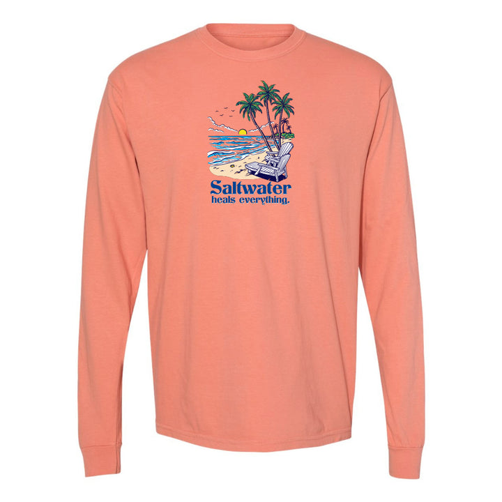 Coral long-sleeve shirt with a beach graphic and 'Saltwater heals everything' text on a white background