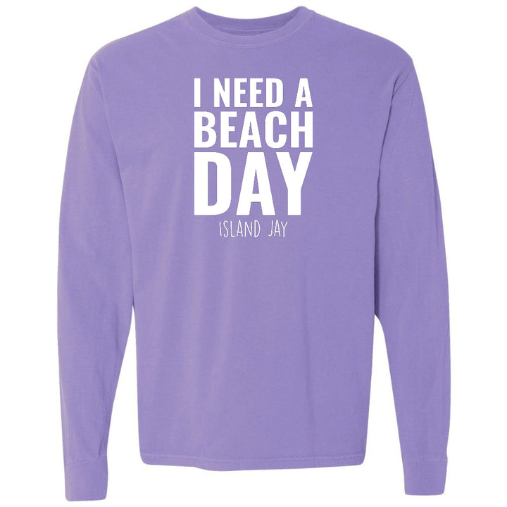 Purple long-sleeve shirt with 'I NEED A BEACH DAY' text on a white background